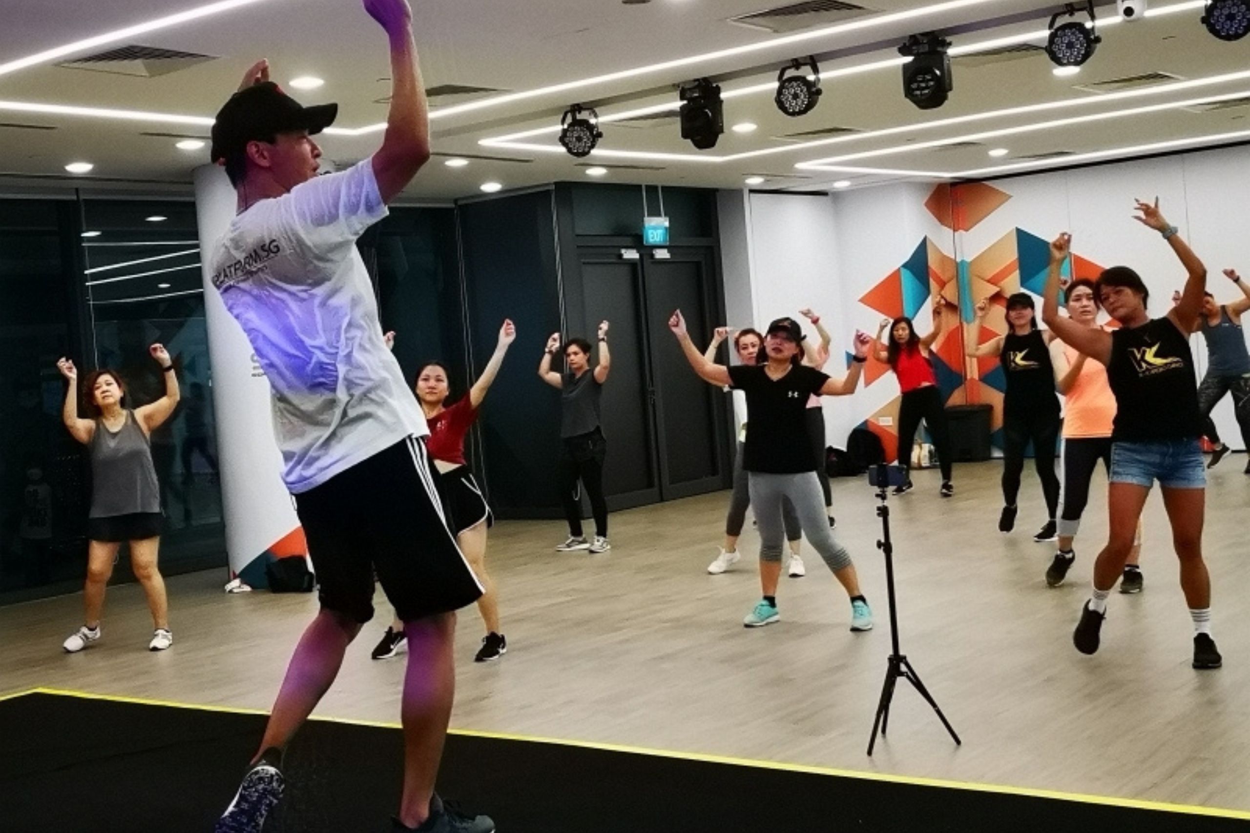 DBD HUB corporate wellness group fitness class in Singapore with a male instructor leading employees through an energetic on-site workout session to promote employee wellness, team bonding, and stress reduction.