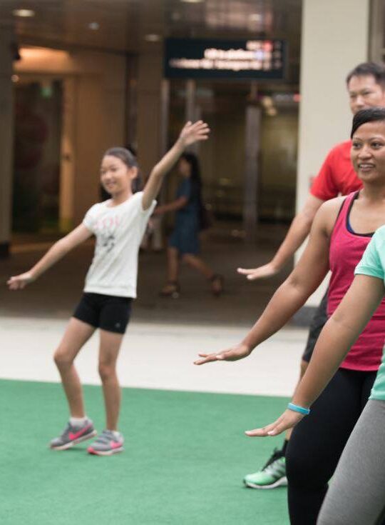Corporate employees engaged in a dynamic group fitness class by DBD Health Hub, promoting physical wellness, teamwork, and workplace energy through expert-led sessions