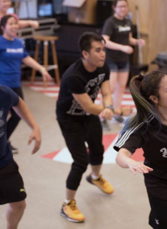 Corporate employees engaged in a dynamic group fitness class by DBD Health Hub, promoting physical wellness, teamwork, and workplace energy through expert-led sessions